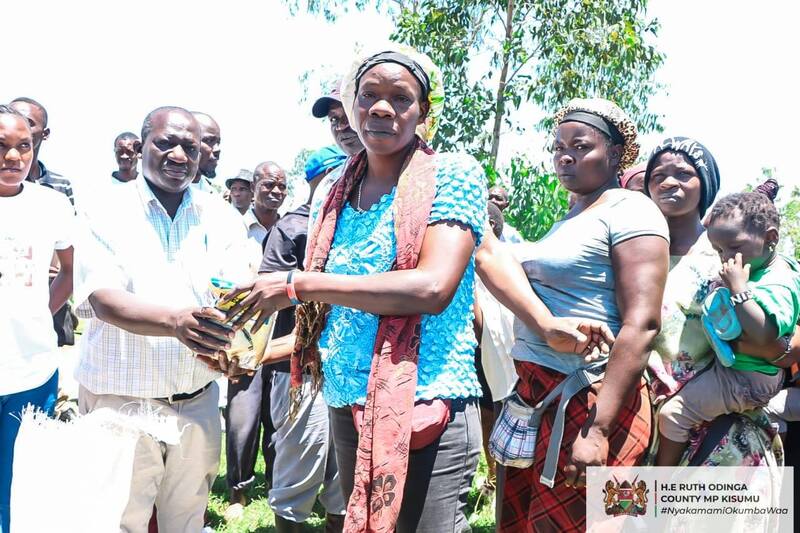 Nyakammi Foundation Manager Mr Solomon Amuti hands over a packet of rice to a farmer in Kapuothe in Nyalenda B